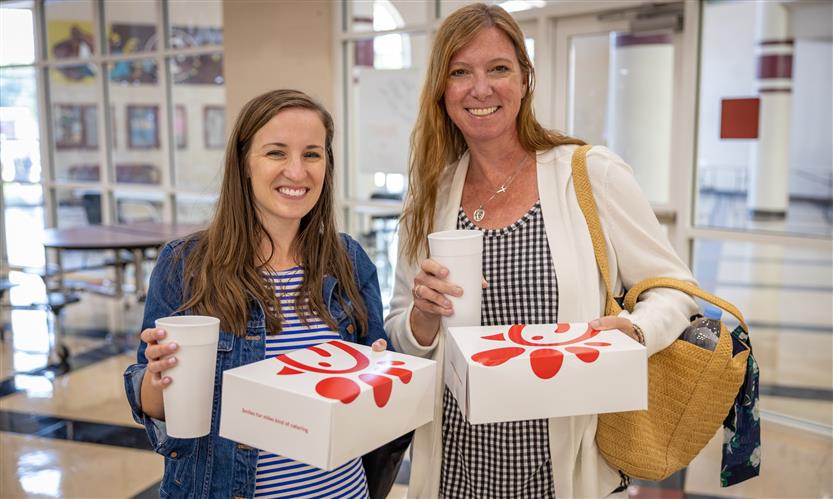 Two teachers holding Chick-fil-A meal boxes smile